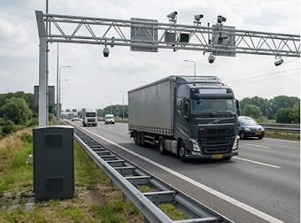 Truck passing under a weigh-in-motion enforcement gantry with cameras and roadside cabinet